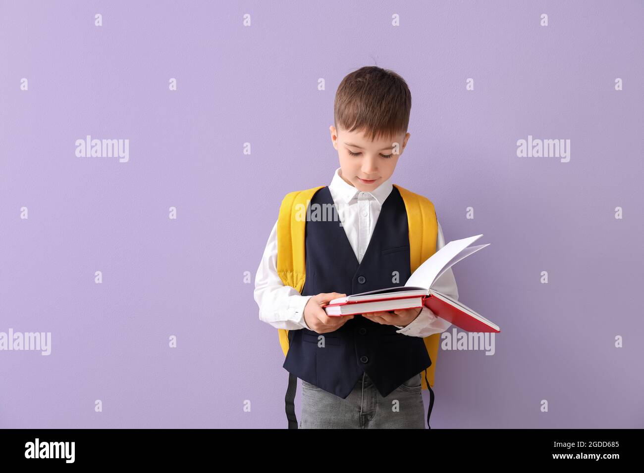 Little schoolboy reading book on color background Stock Photo - Alamy
