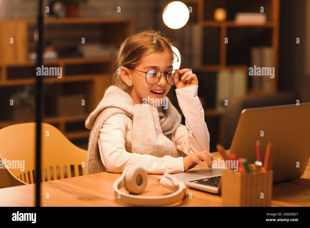 Little girl studying online at home in evening Stock Photo - Alamy