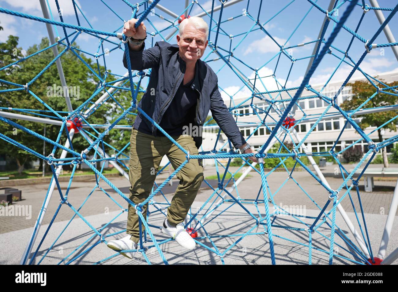 Cologne, Germany. 10th Aug, 2021. Guido Cantz, presenter, stands in a climbing frame in the schoolyard of the Maximilian-Kolbe-Gymnasium. Cantz will be 50 years old on 19.08.2021. (To dpa: 'Rooted between church and sports field - Guido Cantz turns 50') Credit: Oliver Berg/dpa/Alamy Live News Stock Photo