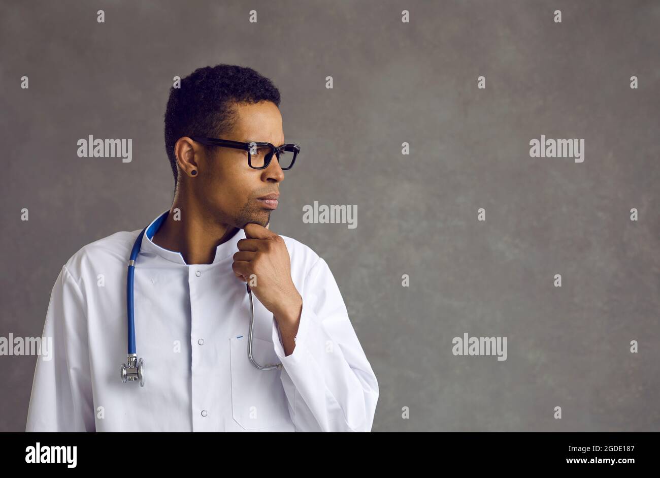 Male african american doctor confused about idea thinking looking aside Stock Photo