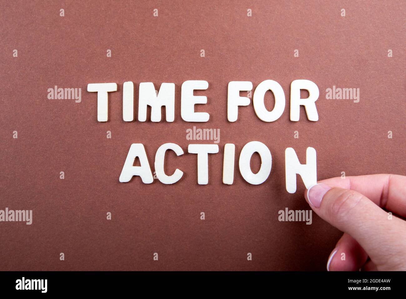Time For Action. White wooden letters with text on a brown background. Stock Photo