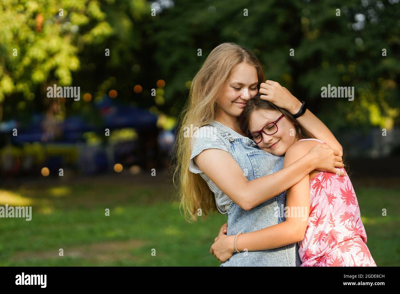 Little girl hugs her older sister. Love and friendship. Happy family concept. Stock Photo