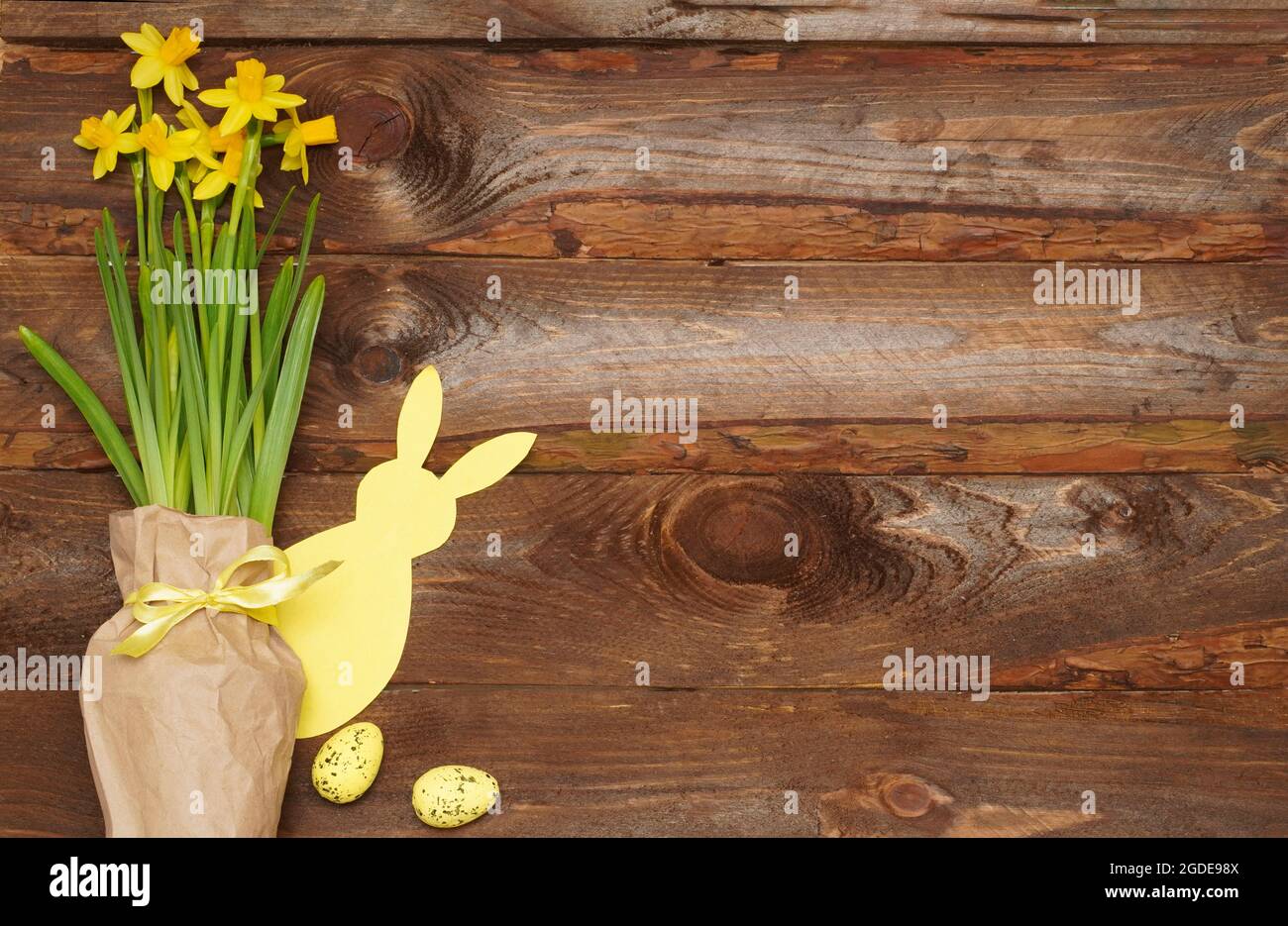 Easter bunny, eggs and spring yellow flower on old wooden background. Easter composition with  copyspace for text. Happy Easter Day concept, greeting Stock Photo