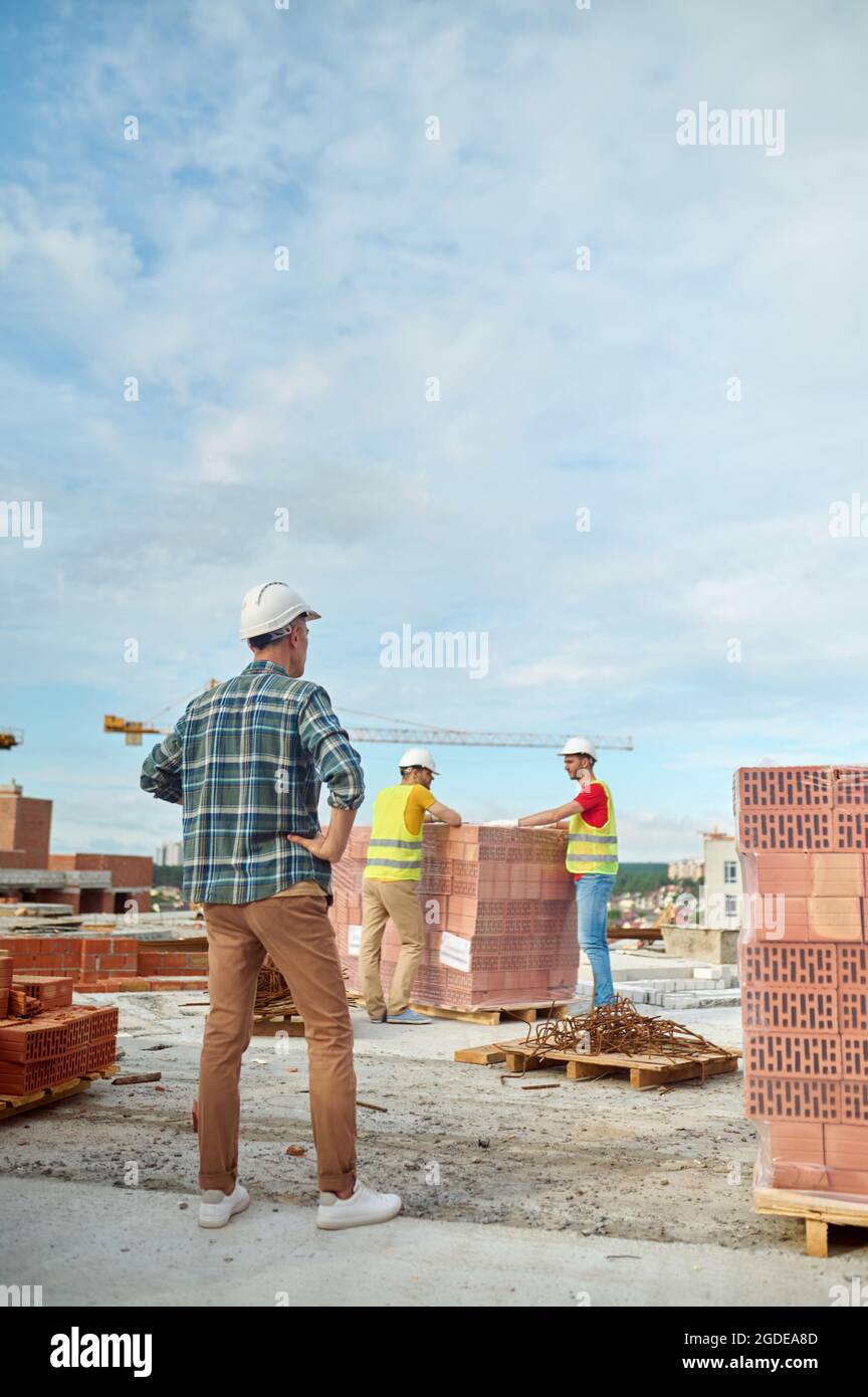 Foreman inspecting the work of two young builders Stock Photo
