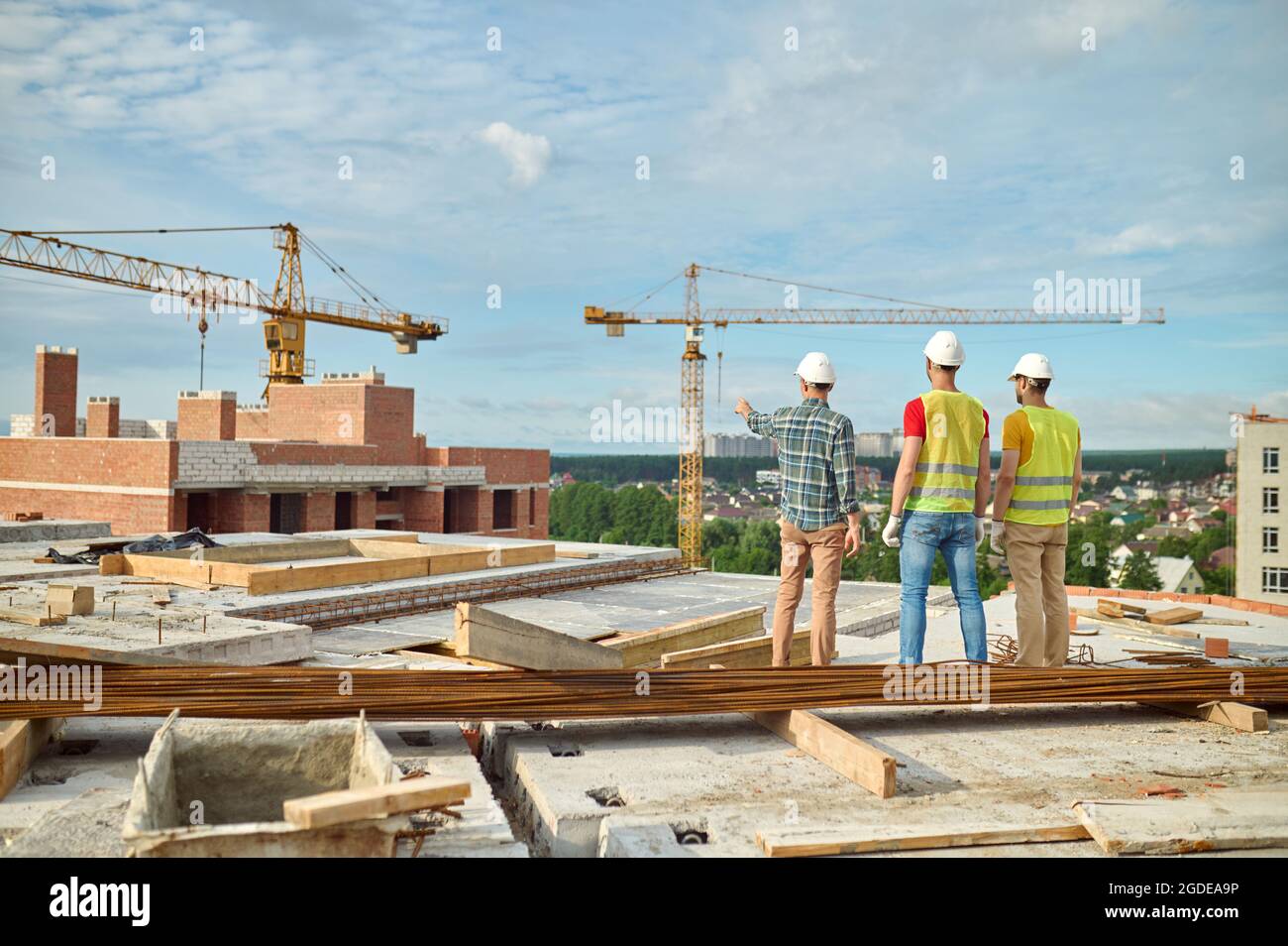 Three men in protective helmets inspecting the building site Stock Photo