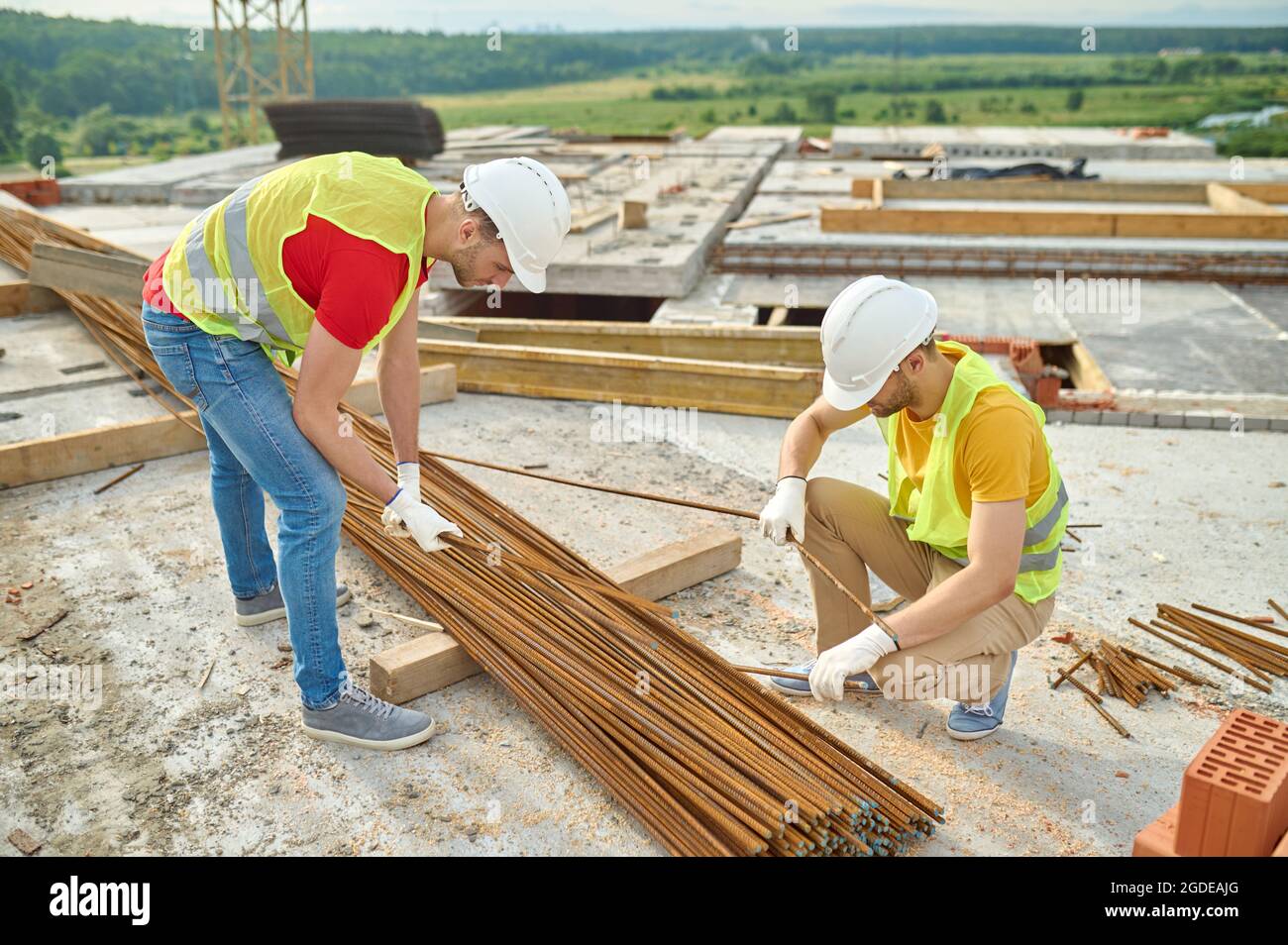 Experienced focused builders in cotton gloves selecting rebars Stock Photo
