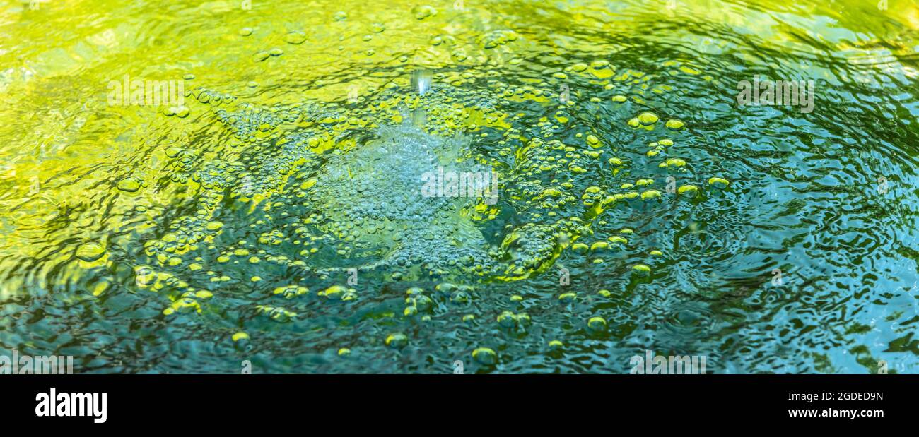 Water drop and bubbles in a cool green water fountain. Background, banner. Stock Photo