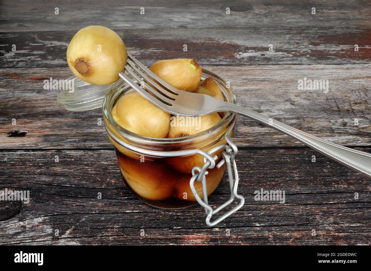 Glass storage jar filled with pickled onions in malt vinegar on a