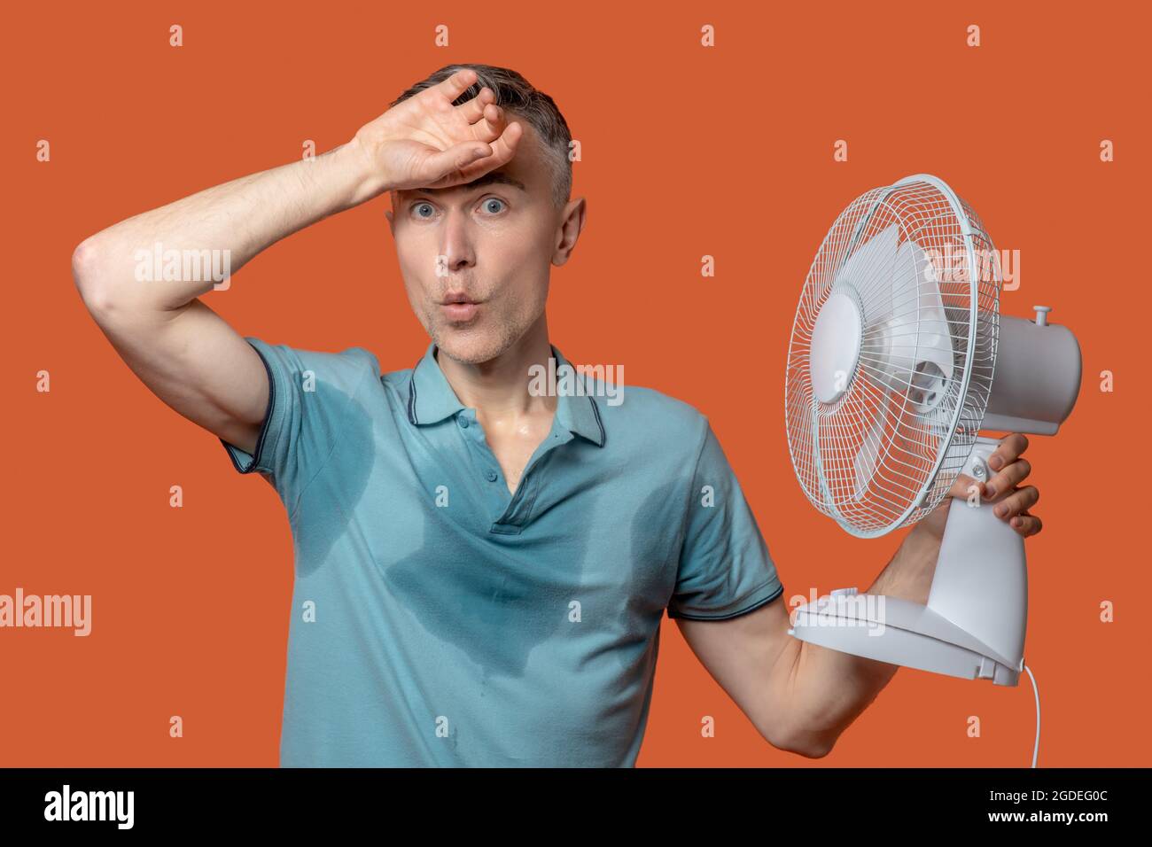 Unhappy man in wet tshirt touching forehead Stock Photo