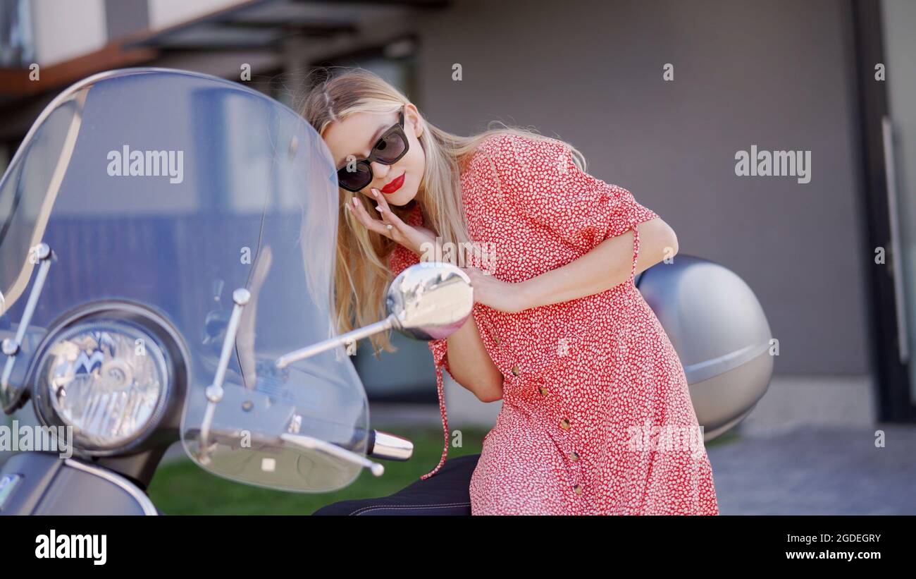 Young woman correcting makeup near scooter Stock Photo