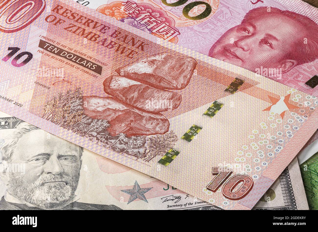 Close up to 10 Dollars of the Republic of Zimbabwe between 50 US Dollar and 100 Yuan banknotes. Ten Dollar banknotes of the African country Zimbabwe. Stock Photo