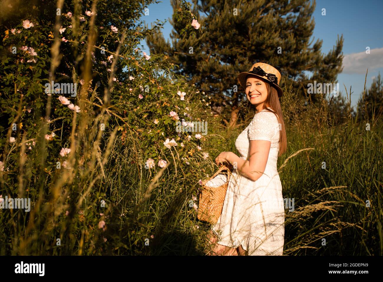 Summer portrait of young woman near wild rose bush Stock Photo