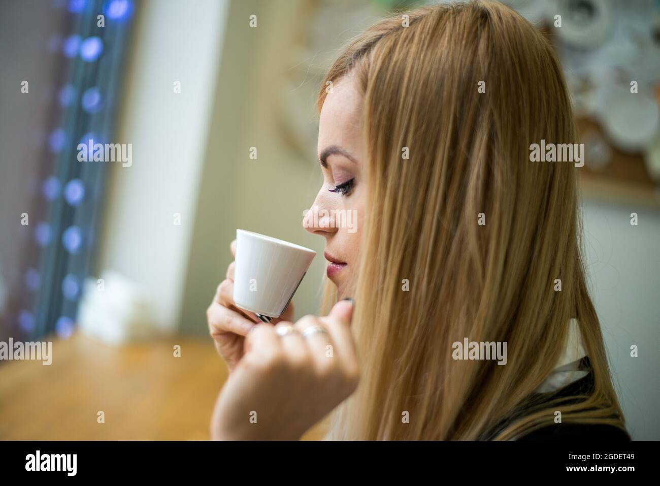 Beautiful blonde girl drinks coffee in the cafe Stock Photo - Alamy