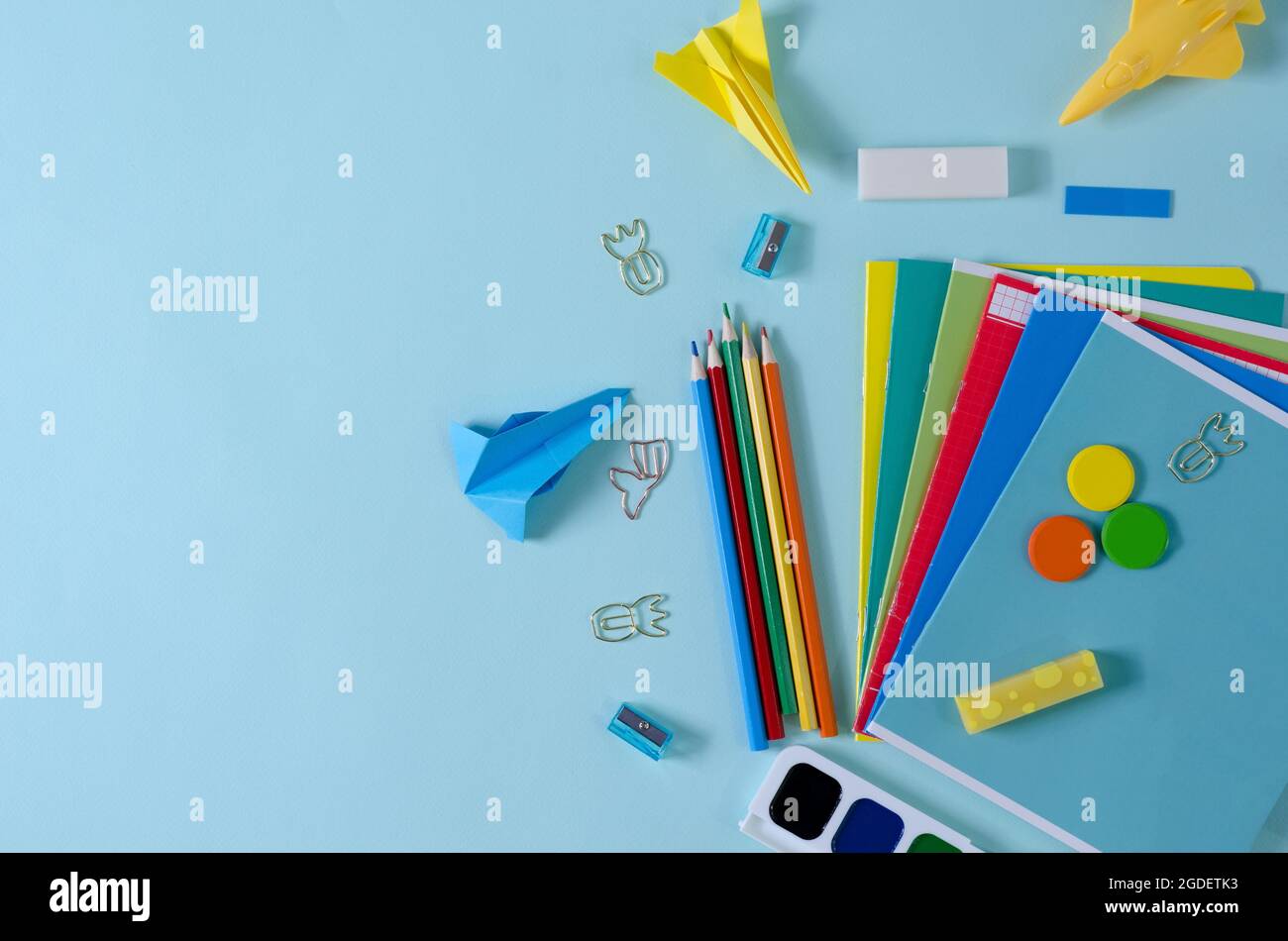 Notebooks, pencils, paints, sharpeners, paper clips - goods for school, office on a blue background Stock Photo