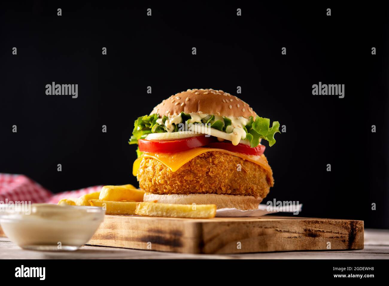 Crispy chicken burger with cheese and french fries on wooden table Stock Photo