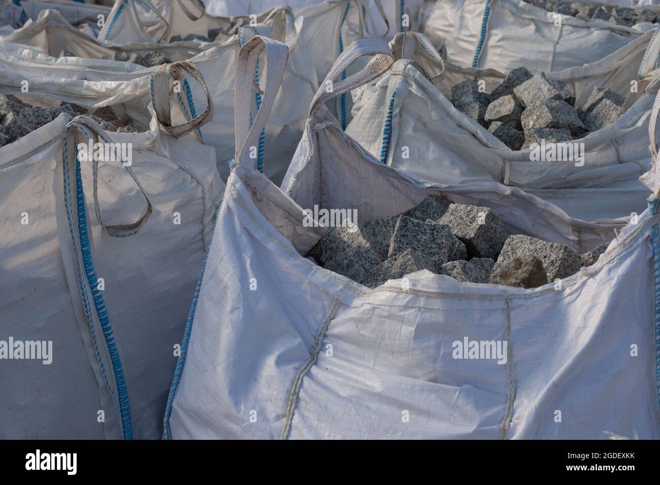 Granite cobblestones in bags. Sacks of grey granite paving cubes, Building materials, bigpack. close-up. Stock Photo