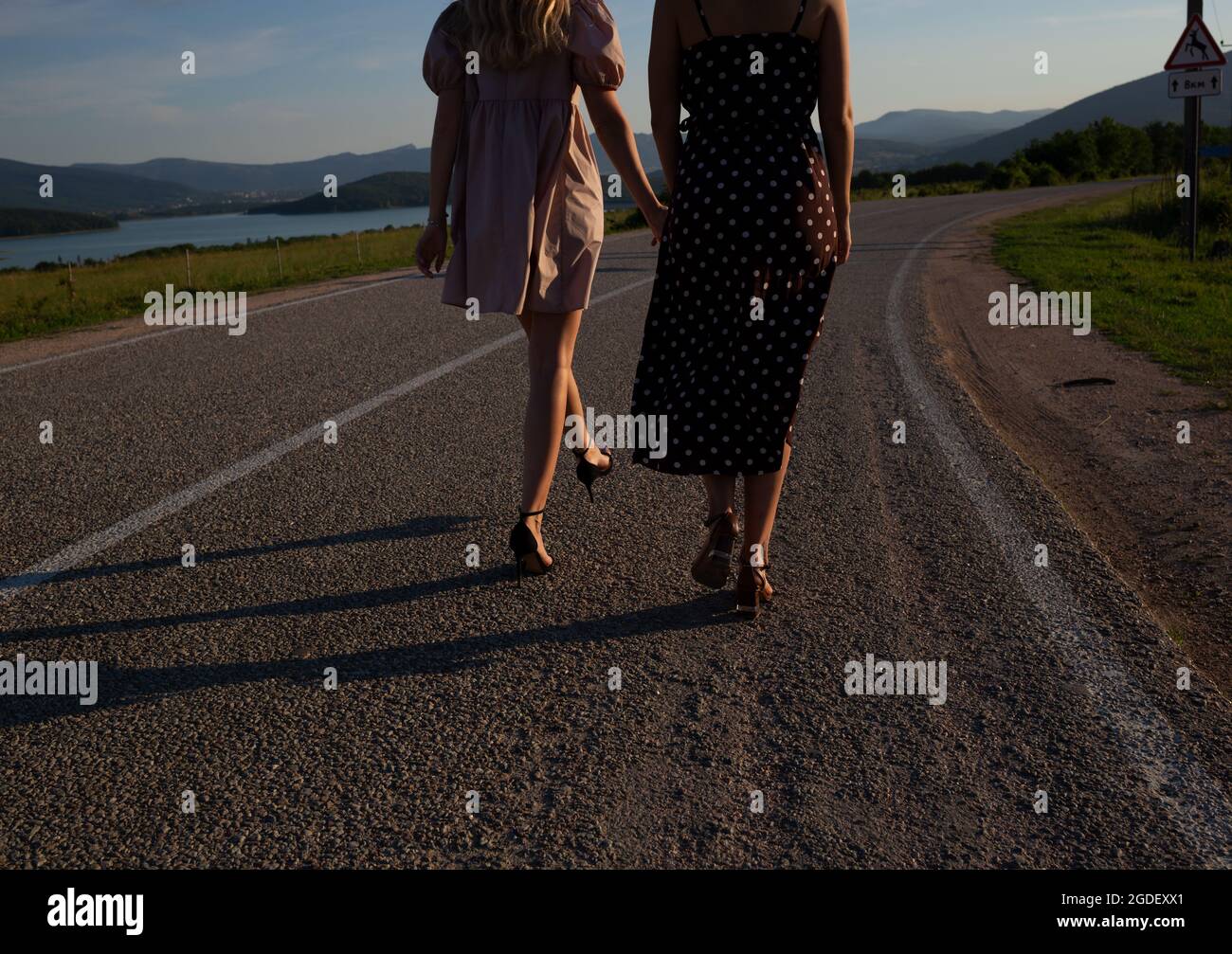 two girls walking down the road holding hands Stock Photo - Alamy