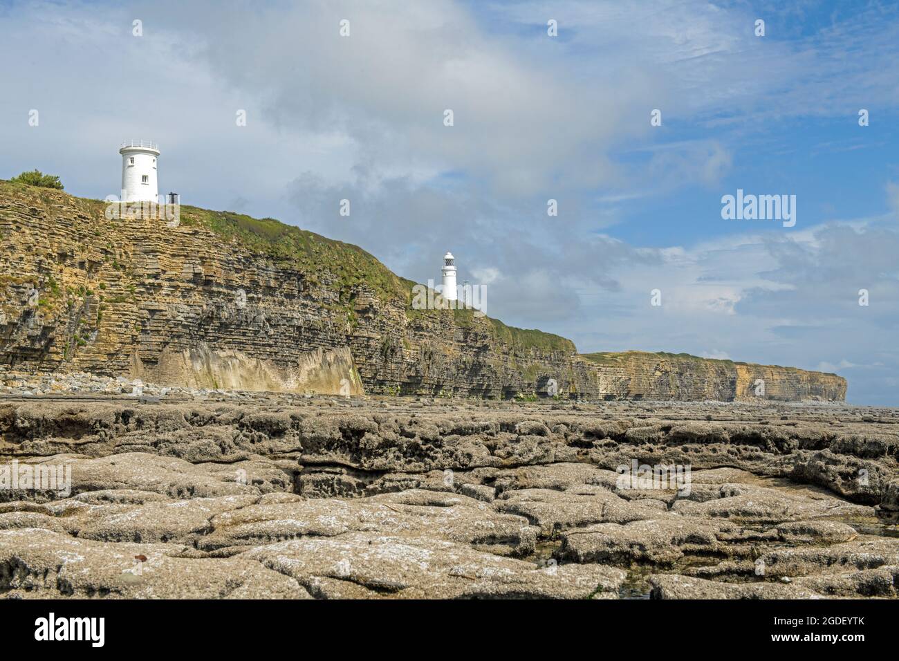 Nash Point beach and rocks with two lighthouses looking over the Bristol Channel. The left lighthouse is disused. Stock Photo