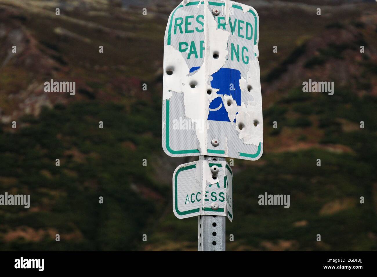 reserved parking sign for disabled with several shots by a firearm in Alaska, USA. Stock Photo