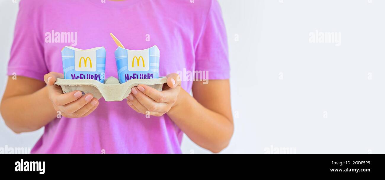 Woman in a purple t-short holding an ice cream Mcflurry. Delivery McCafe. fast food restaurant Mcdonalds. Take away ice cream Mcflurry Stock Photo