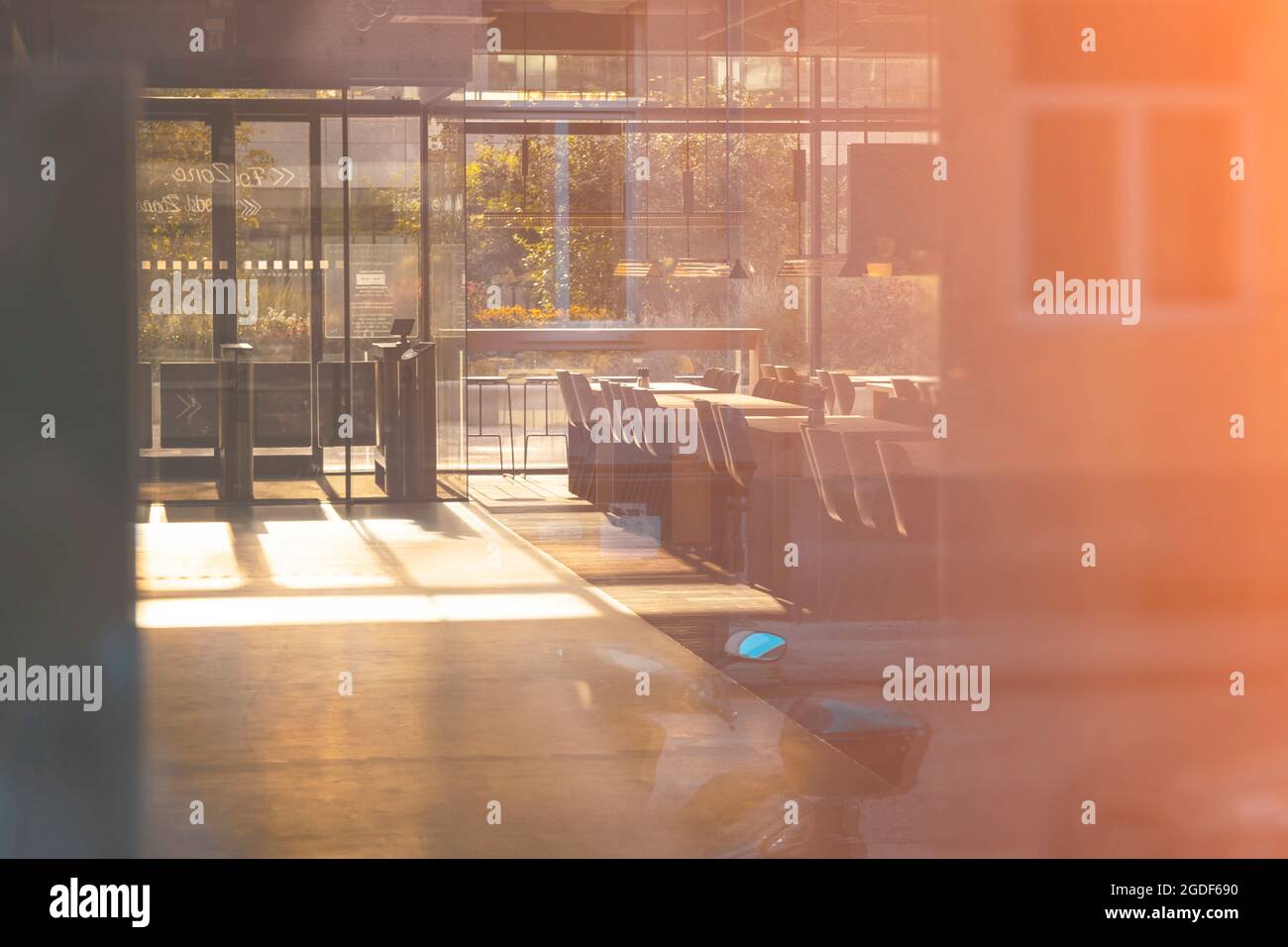 View into an empty cafe through the glass with reflection. Morning light shining spring. Stock Photo