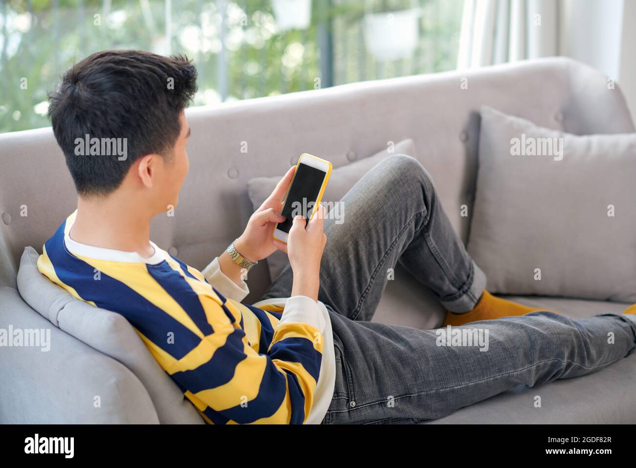 Happy an Asian man with beautiful smile is looking at the mobile phone chatting with someone with happy moment Stock Photo