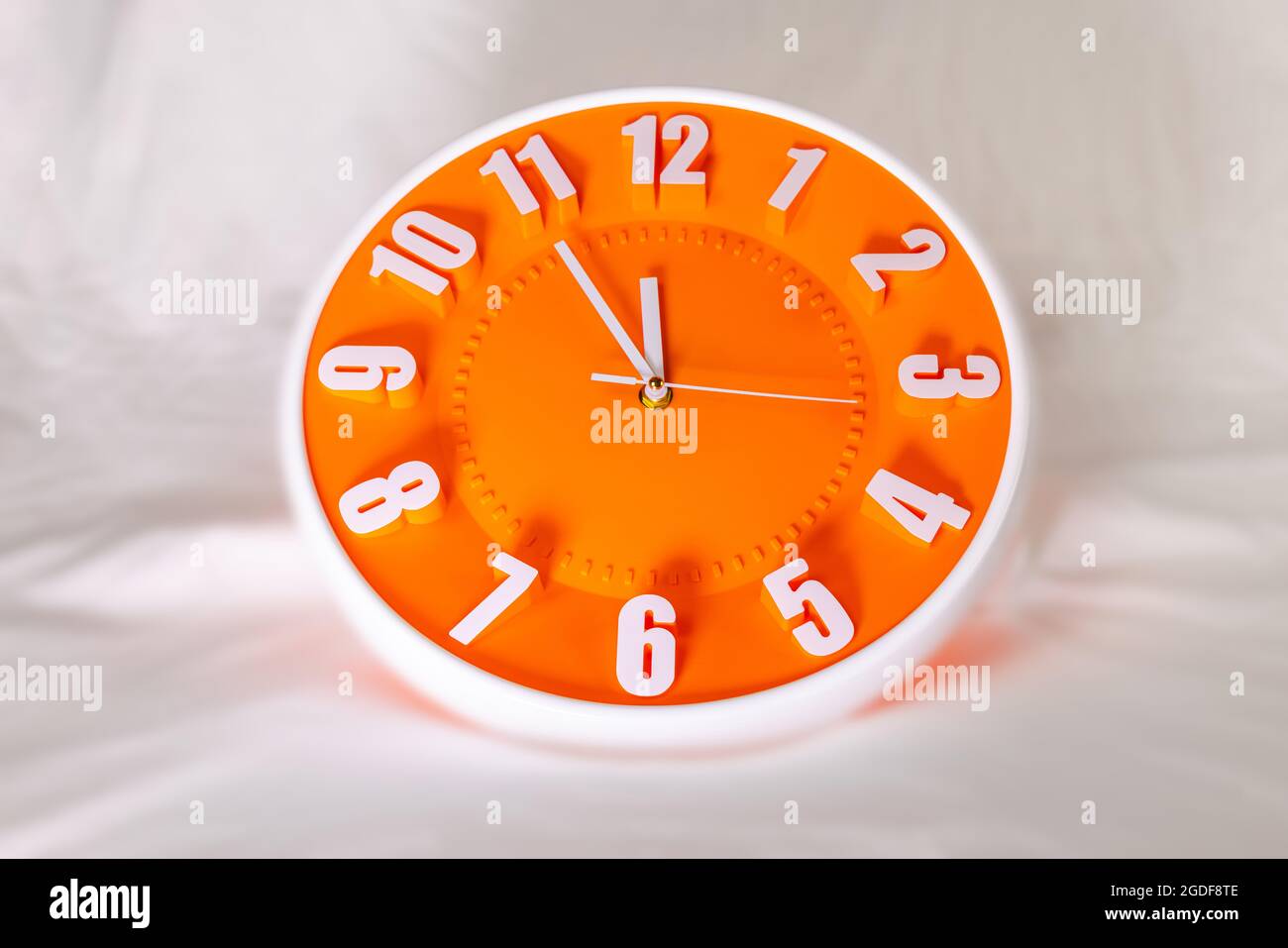 Orange Wall Clock on white blur background. Shadows over the clock face