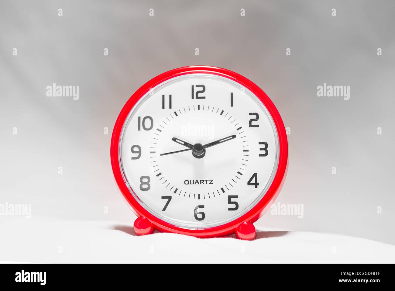 Small red alarm clock show the running time. A modern clock with red frame. Smile face of a clock. Close up on a red plastic watch with second pointer Stock Photo