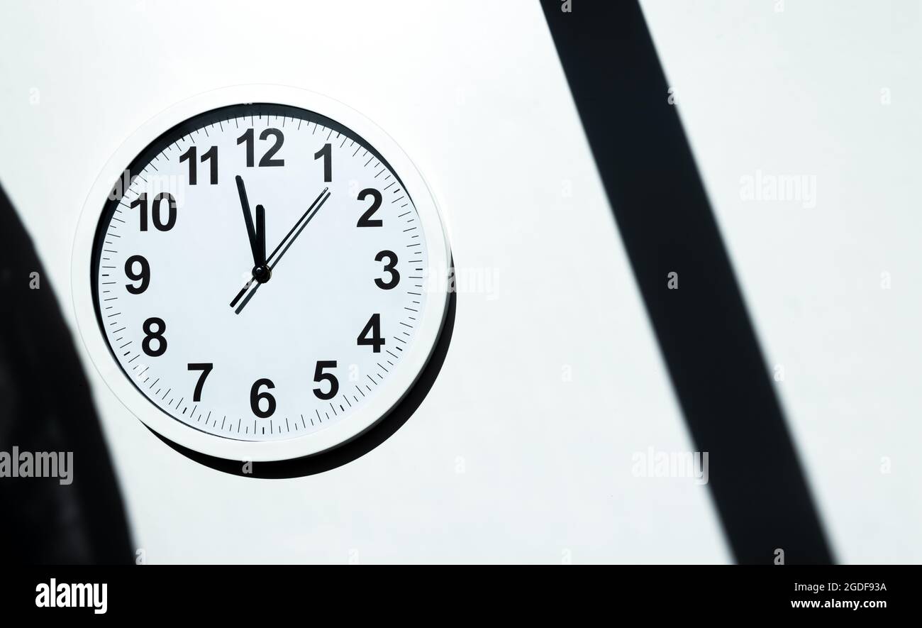 White clock face of a wall clock show the time. It's close to 12 o'clock. The latest report of the atomic scientist shows the doomsday clock 100 secon Stock Photo