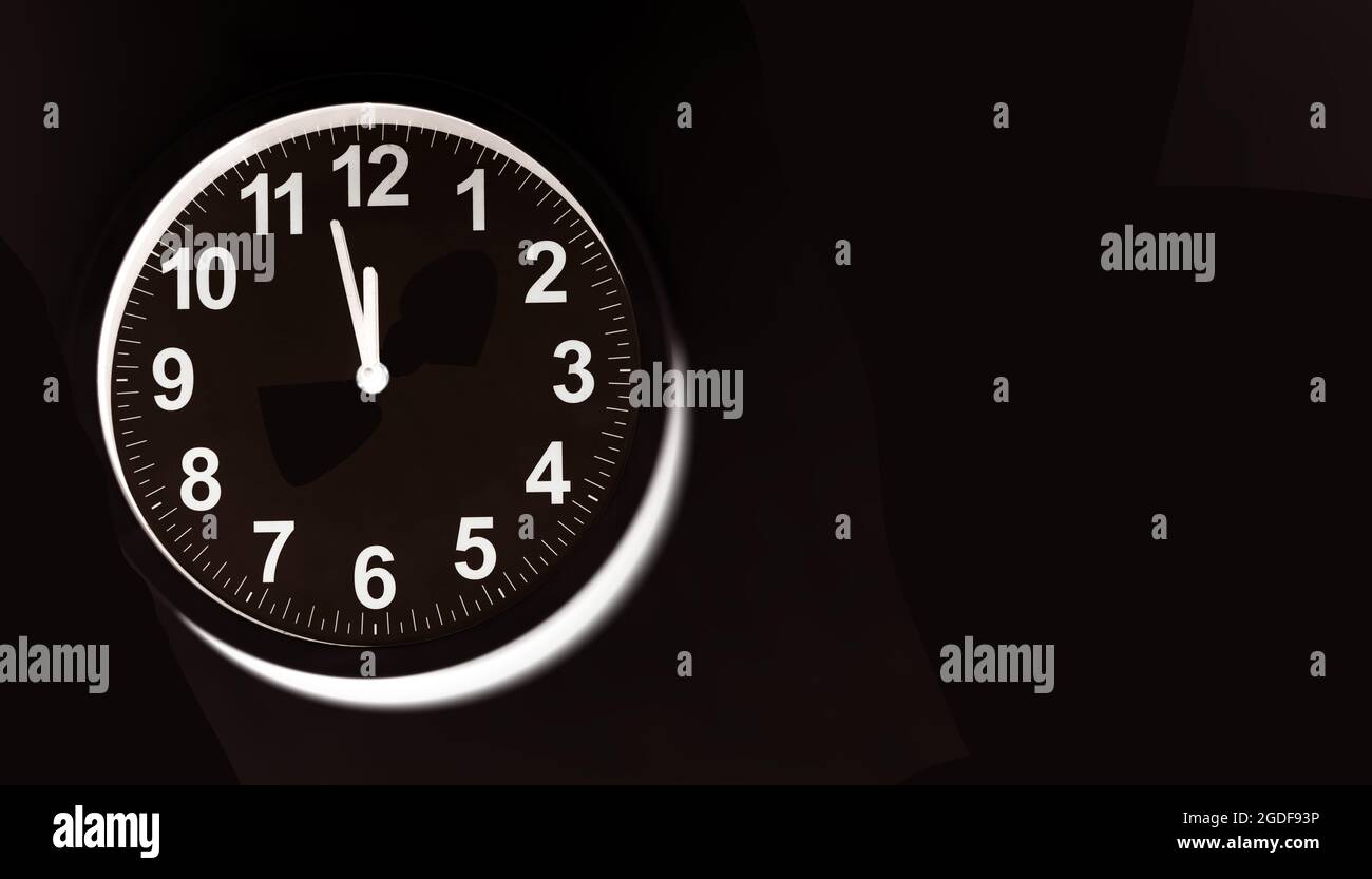 Black clock face of a wall clock show the time. It's close to 12 o'clock. The latest report of the atomic scientist shows the doomsday clock 100 secon Stock Photo