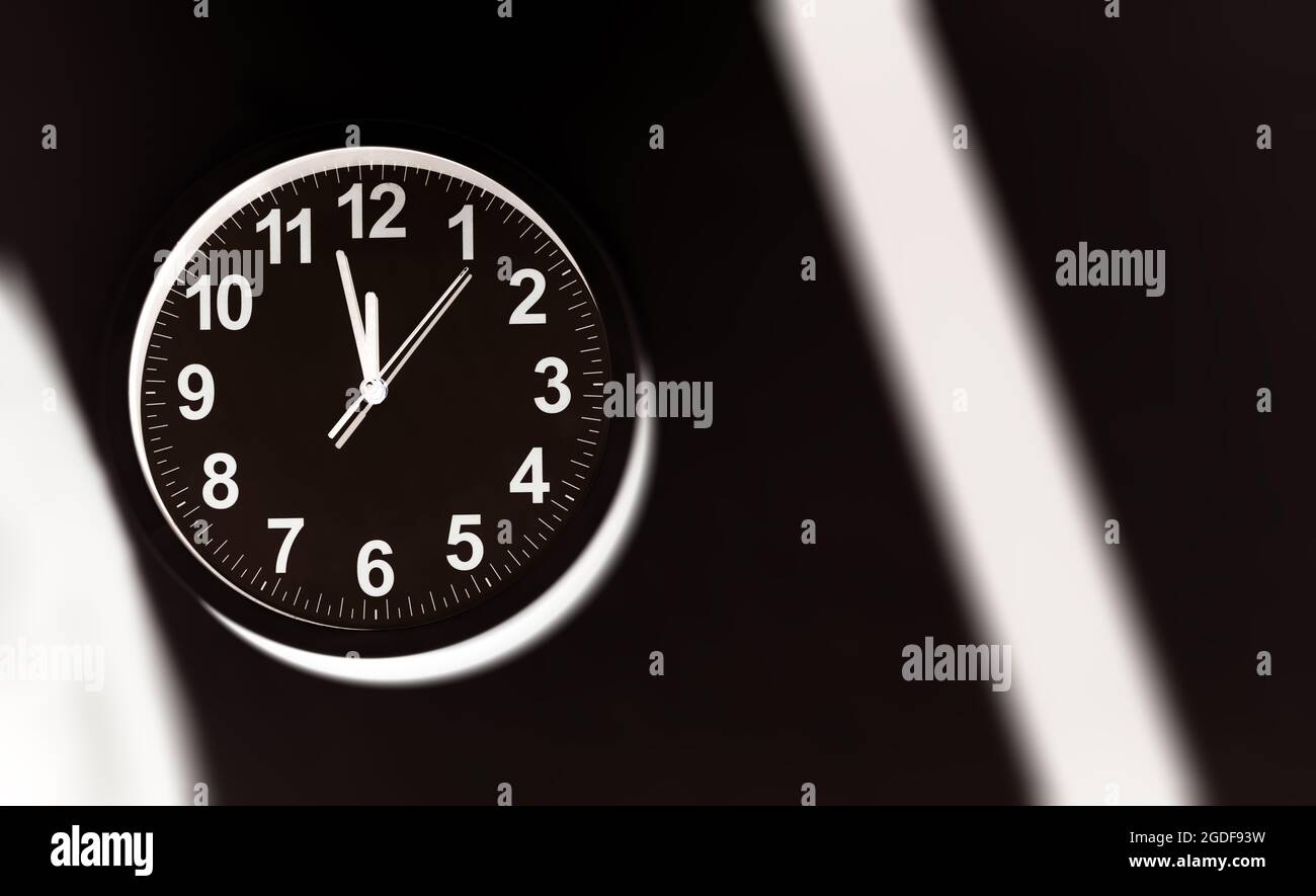 Black clock face of a wall clock show the time. It's close to 12 o'clock. The latest report of the atomic scientist shows the doomsday clock 100 secon Stock Photo