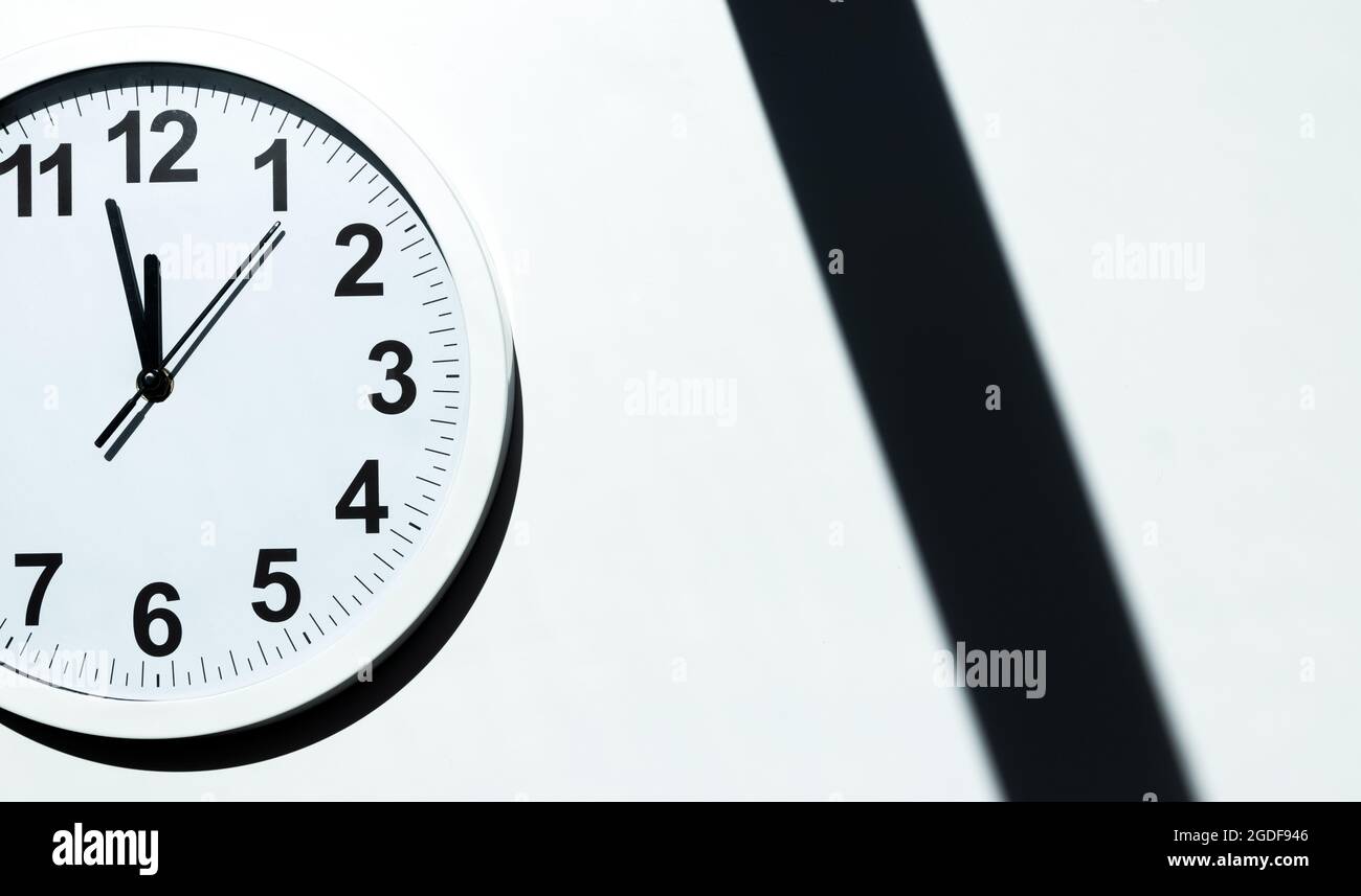White clock face of a wall clock show the time. It's close to 12 o'clock. The latest report of the atomic scientist shows the doomsday clock 100 secon Stock Photo