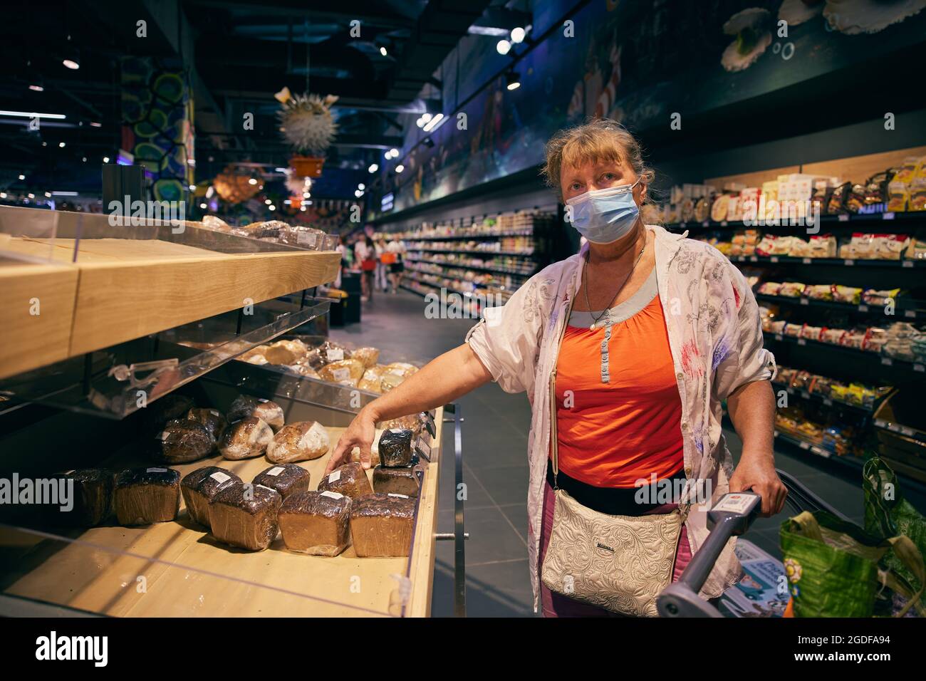 A pretty senior woman in a medical mask selects bread in a grocery store. Odessa Ukraine, Silpo grocery store. Stock Photo