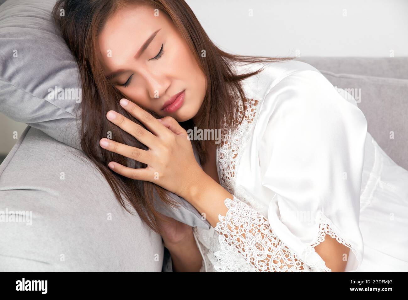 Asian woman in a satin sleepwear whitered-faced because of fever and feverish at night. Body Temperature Stock Photo