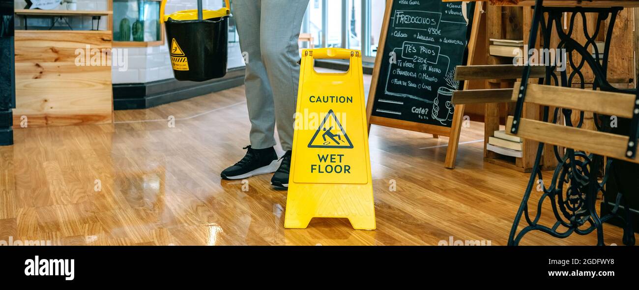 Worker placing wet floor sign after mopping Stock Photo