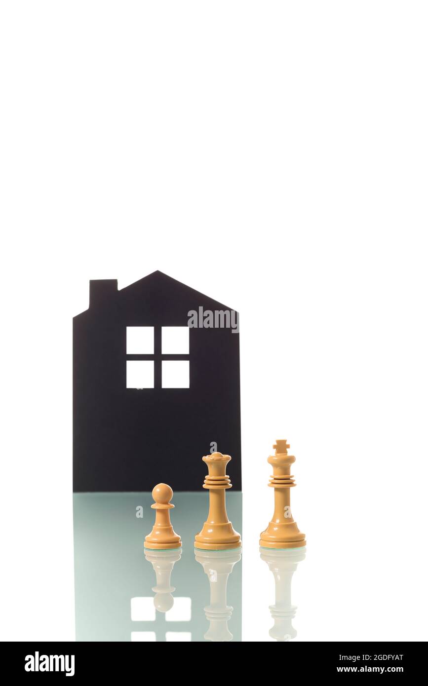 Conceptual photograph of two white chess pieces (king and queen) metaphorically representing a white heterosexual couple with a child, with the silhou Stock Photo