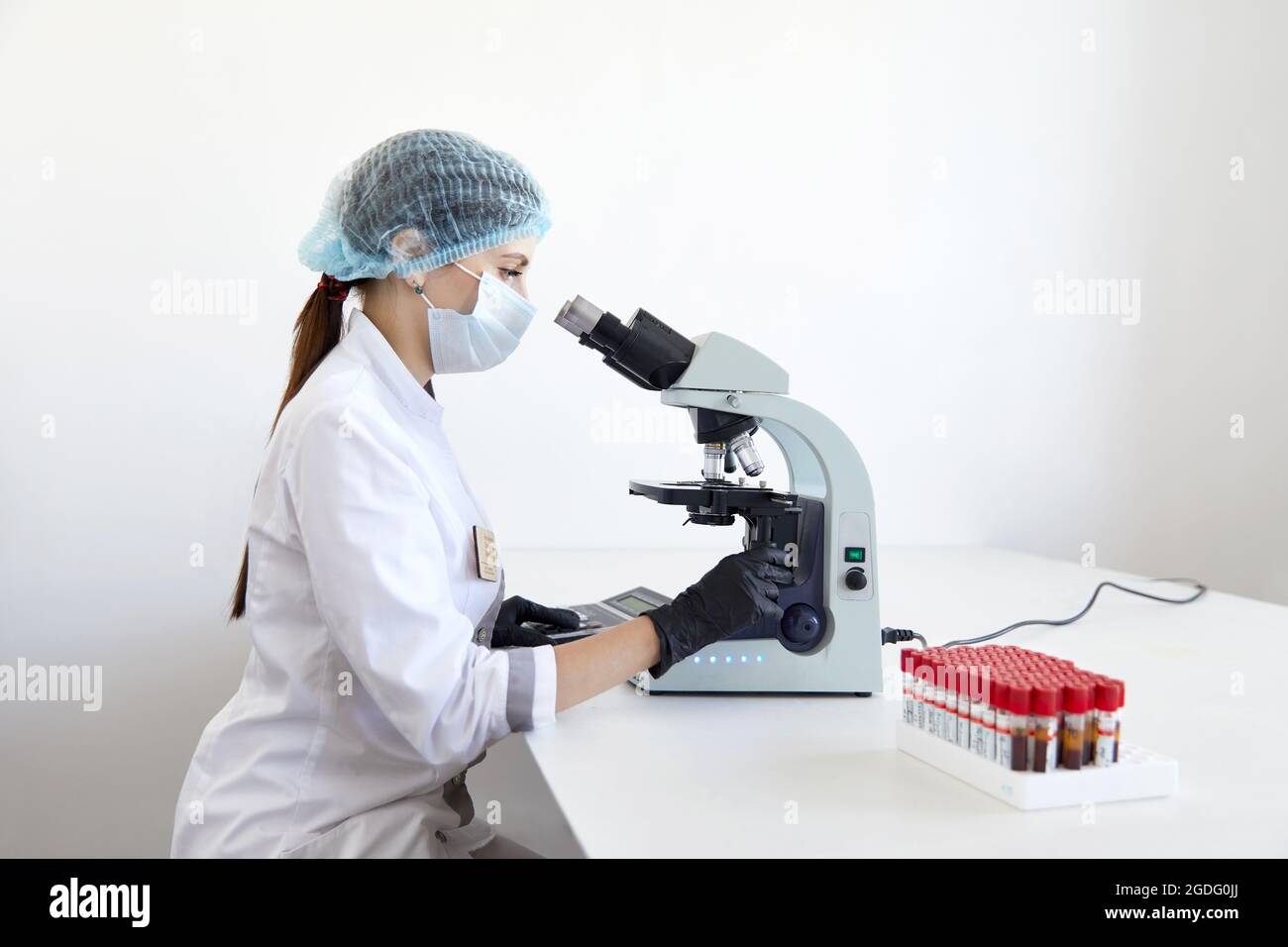 Female scientist looking through microscope in modern chemical ...