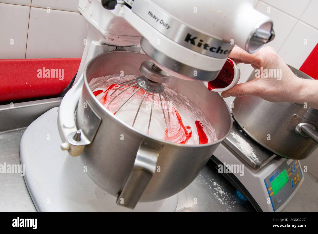 Adding red food colouring to egg white to create the base for macarons