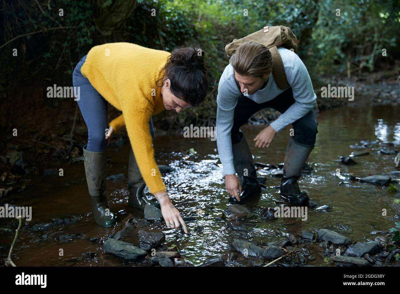 Hiker couple walking in stream Stock Photo