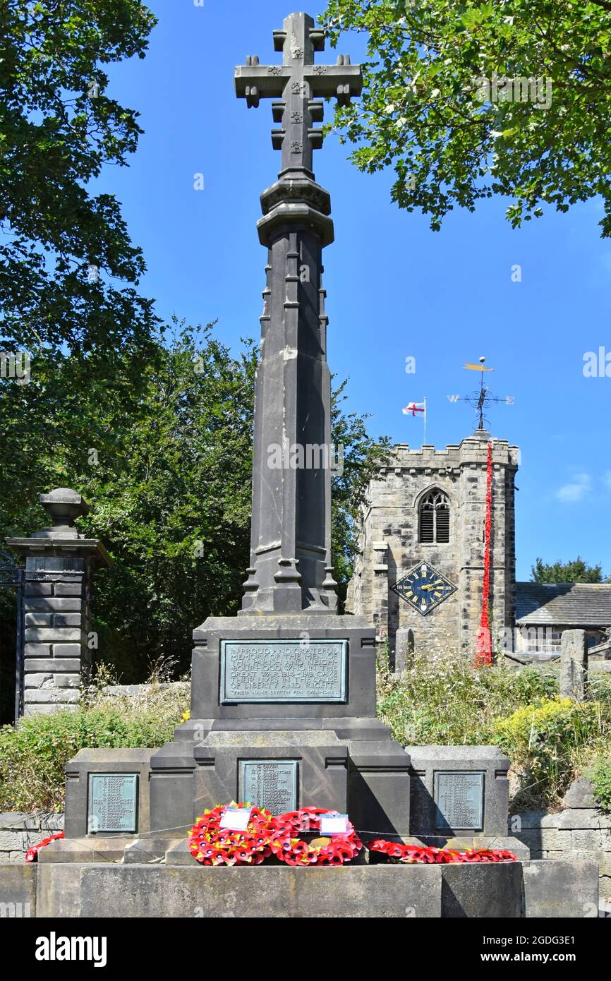 Remembrance end of First World War red poppy cascade falls from top St Andrews Church clock tower beyond war memorial wreaths   Kildwick Yorkshire uk Stock Photo