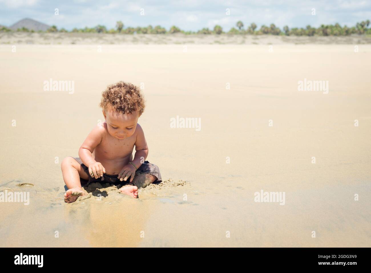 Toddler playing in sand on beach Stock Photo
