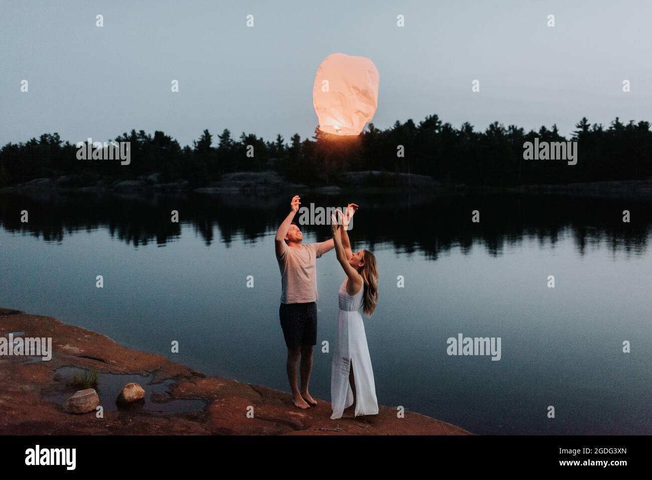 Couple releasing sky lanterns by lake, Algonquin Park, Canada Stock Photo