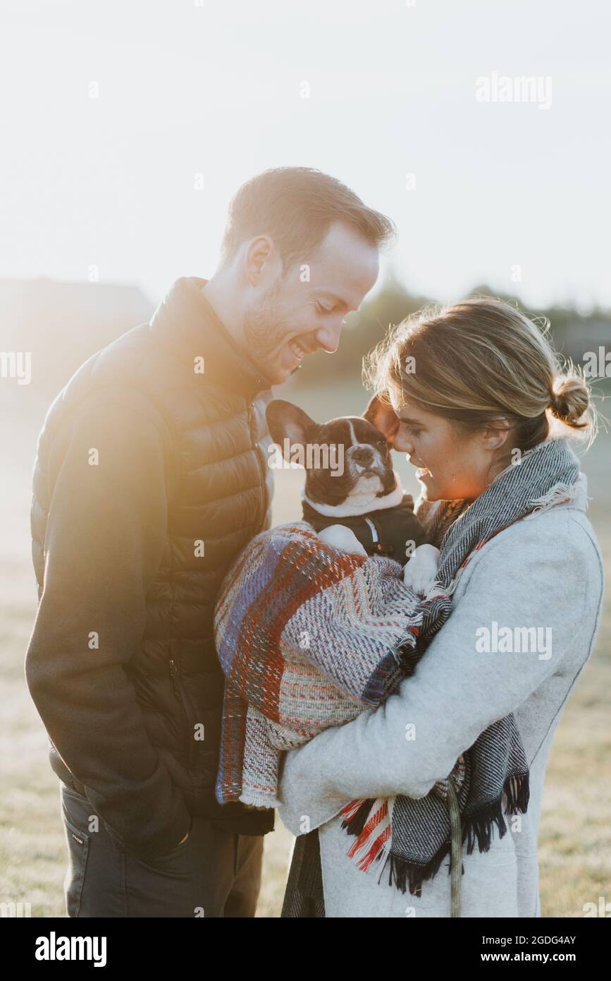 Couple carrying their puppy in woollen blanket Stock Photo