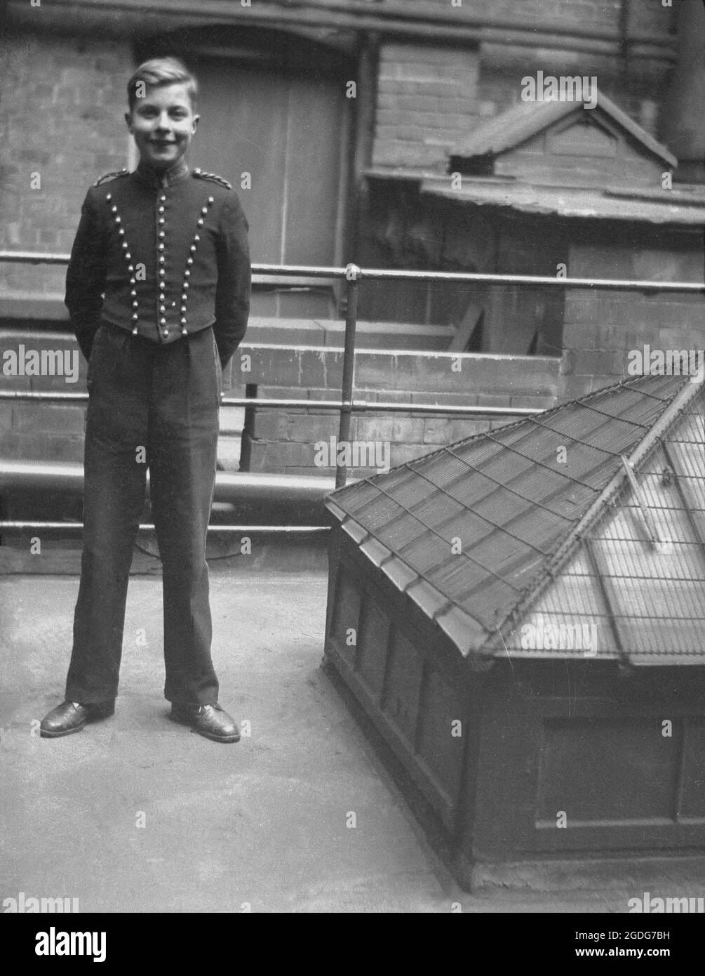 1940s, historical, a hotel bellboy in his uniform standing on a flat roofed area beside an air vent, London, England, UK. A bellboy was traditionally an adolescent male, hence the tern bellboy, who was on call to run general errands and to be of assistance for guests during their stay, as well carrying luggage to and from their rooms, when they checked in and out. Stock Photo