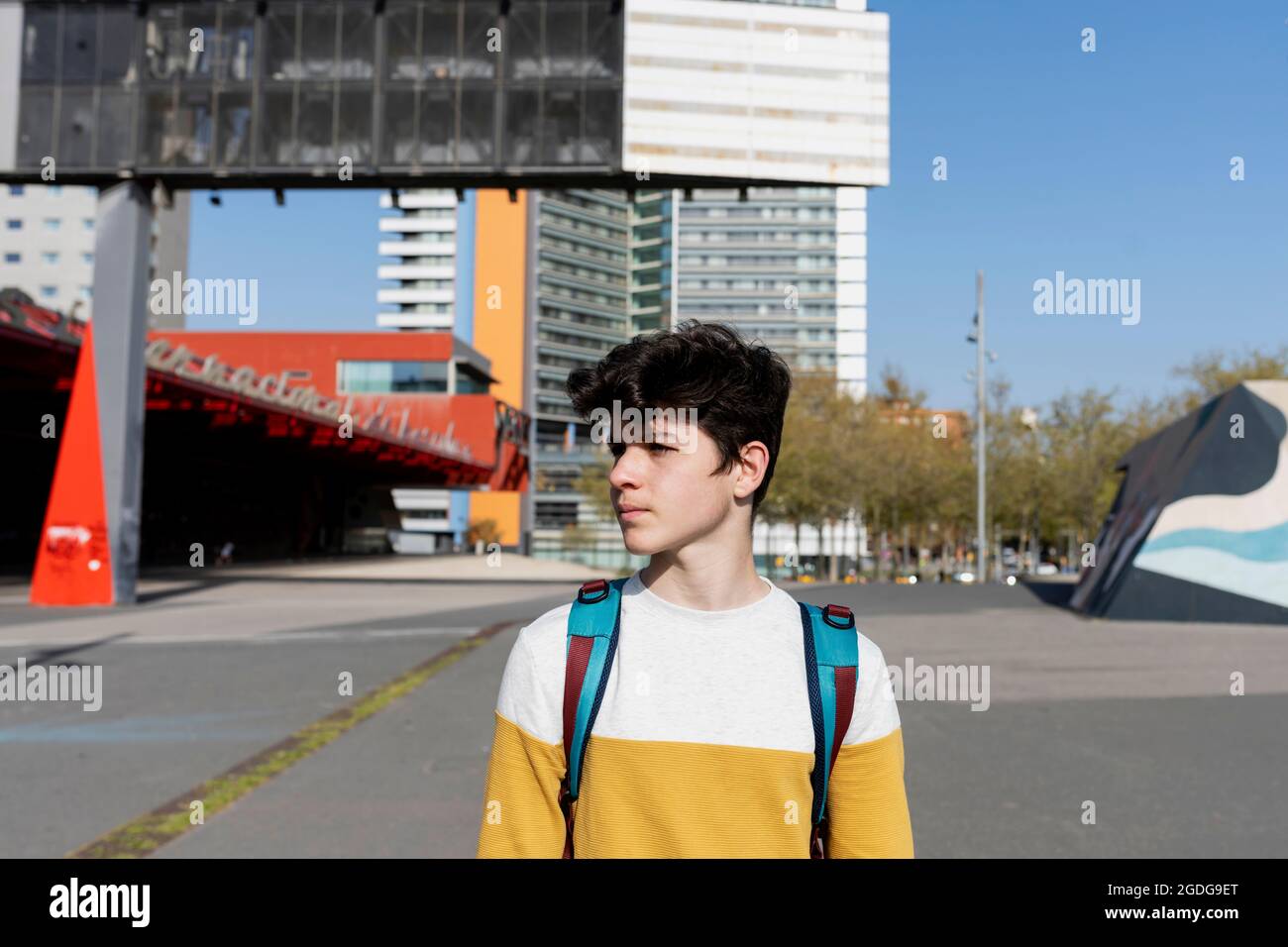 Young teen male standing on the street wearing a backpack Stock Photo