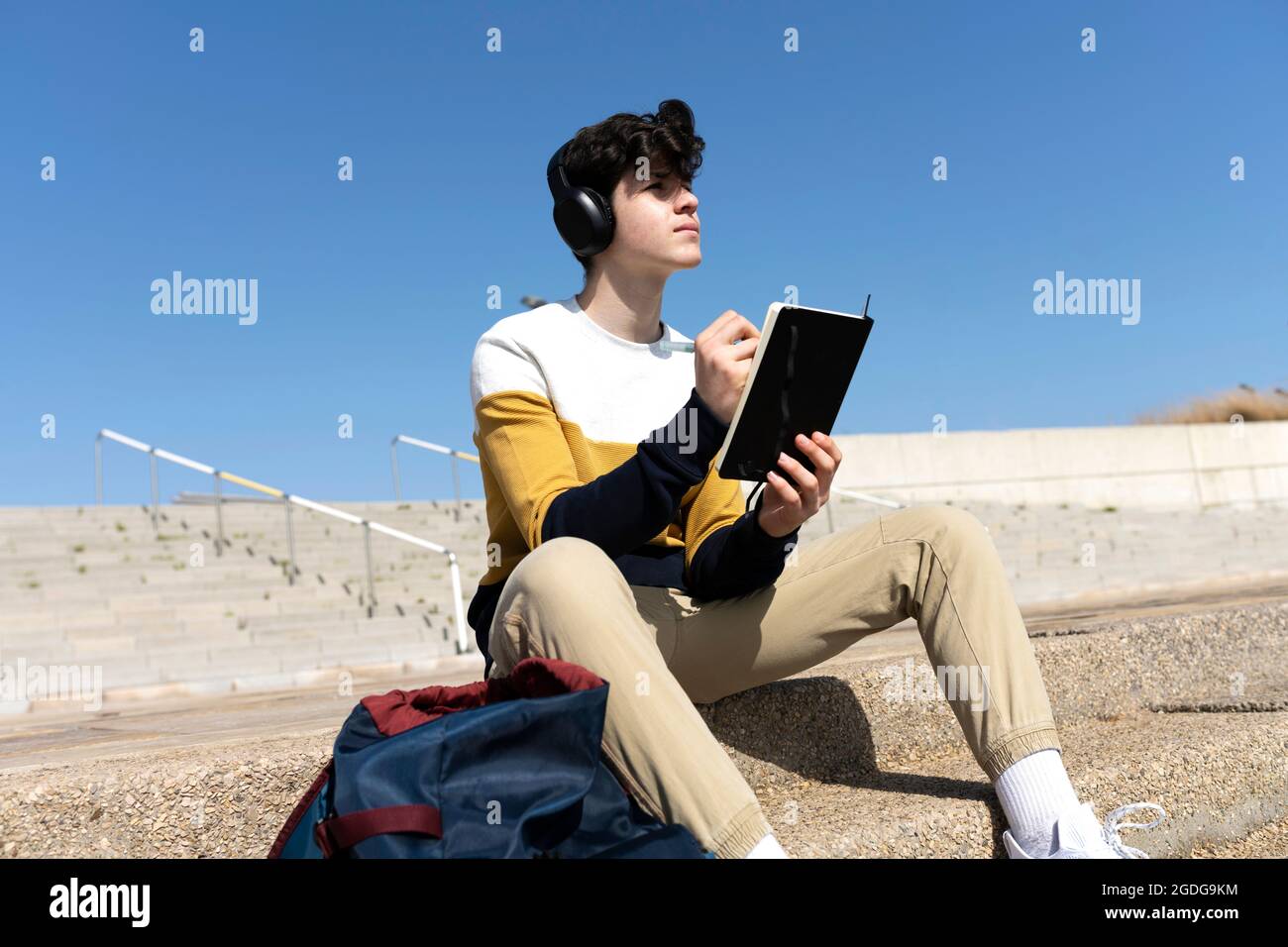 Young male writing notes in a notebook sitting on a staircase Stock ...