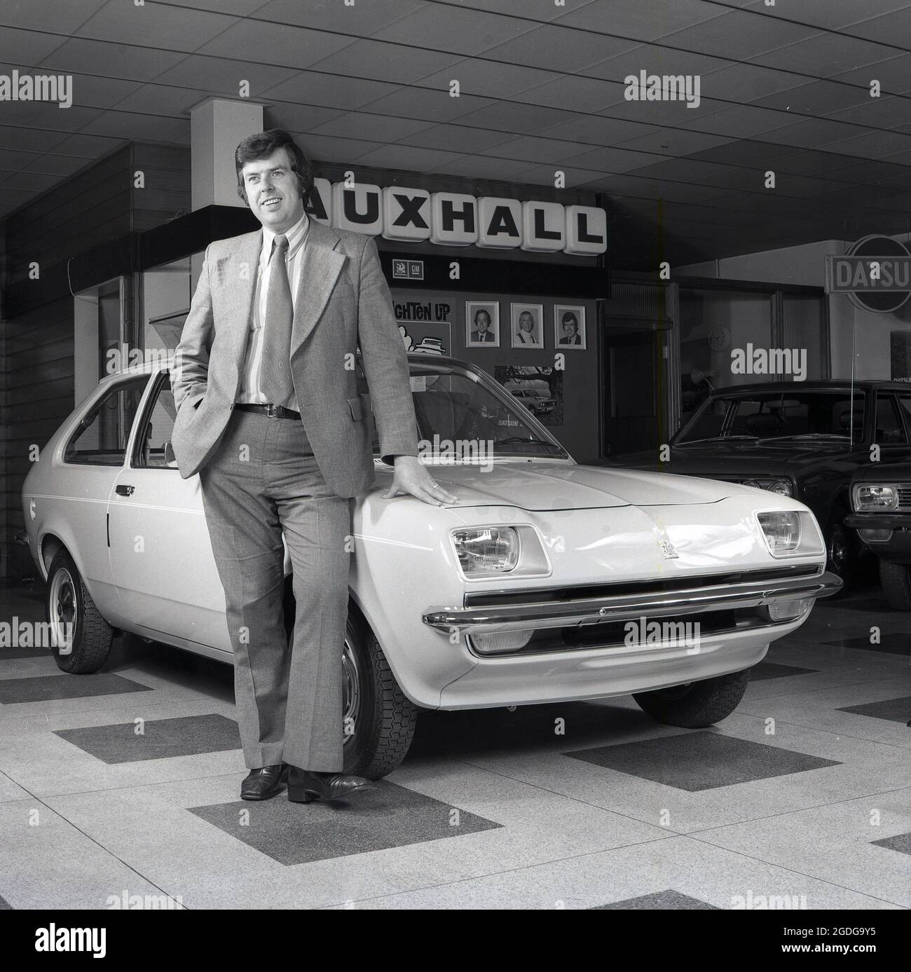 1975, historical, a car salesman in a showroom standing next to a new car, a Vauxhall Chevette 3-door hatchback, Croydon, England, UK. Made at Ellesmere Port in Cheshire under a Government inititative to bring jobs to the area, the Chevette was in production from 1975 to 1984 and was Britain's best selling hatchback in the three years to 1978. The 1970s were a time when compact hatchback cars were a popular vehicle. Stock Photo