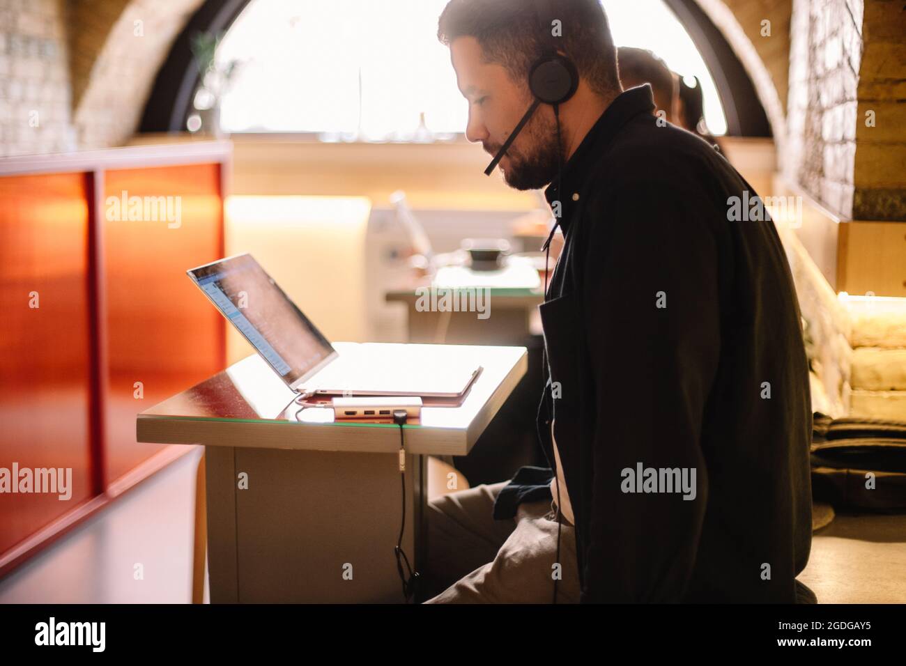 Man in headphones using laptop computer at cafe Stock Photo
