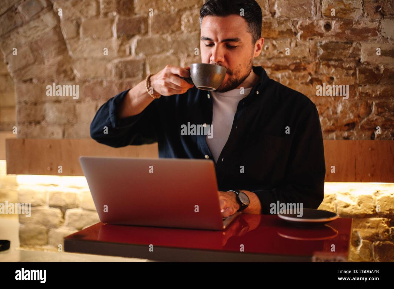 businessman drinking coffee while using laptop computer at cafe Stock Photo
