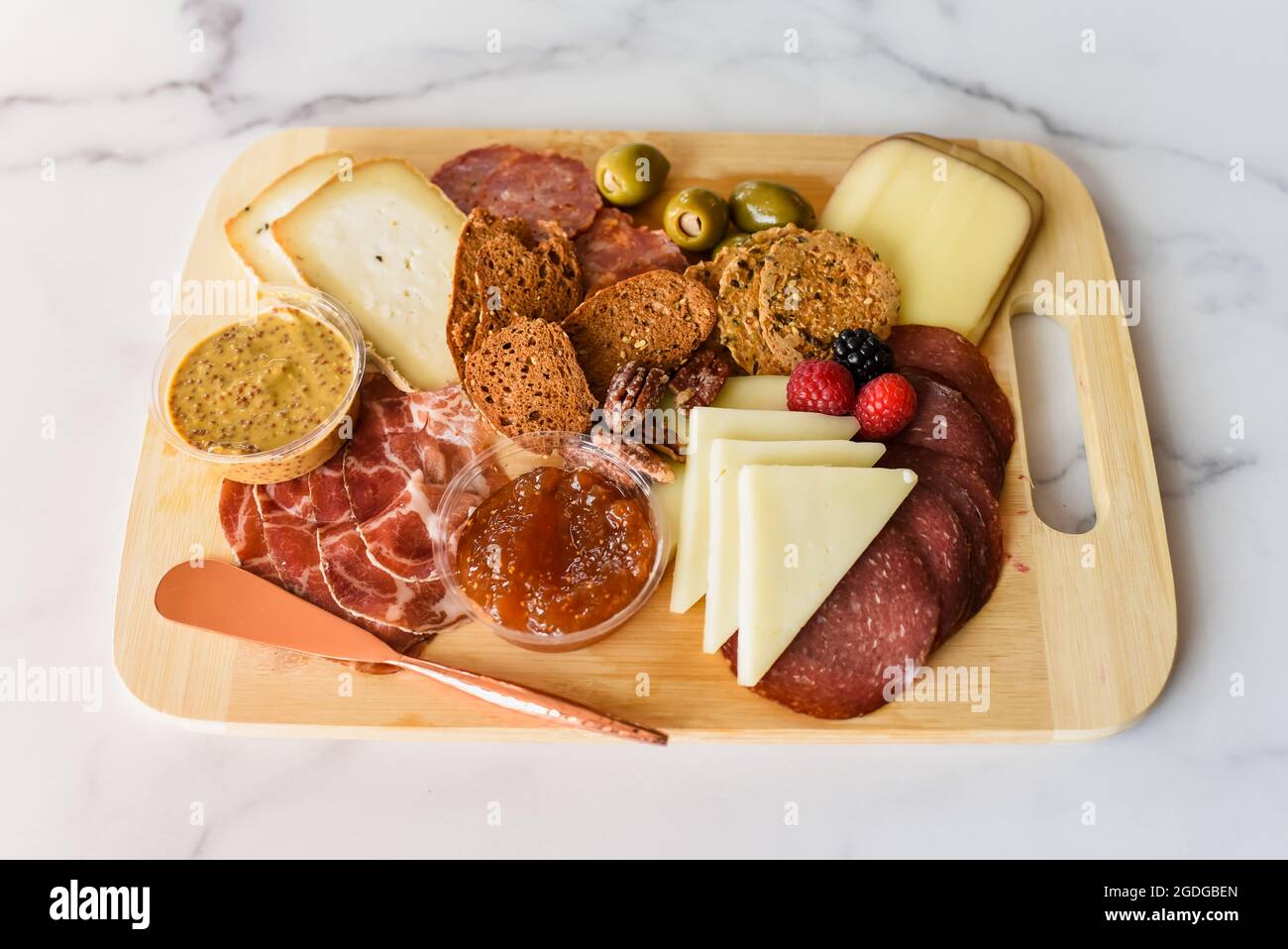 Charcuterie board of meat, cheese and crackers on white marble Stock